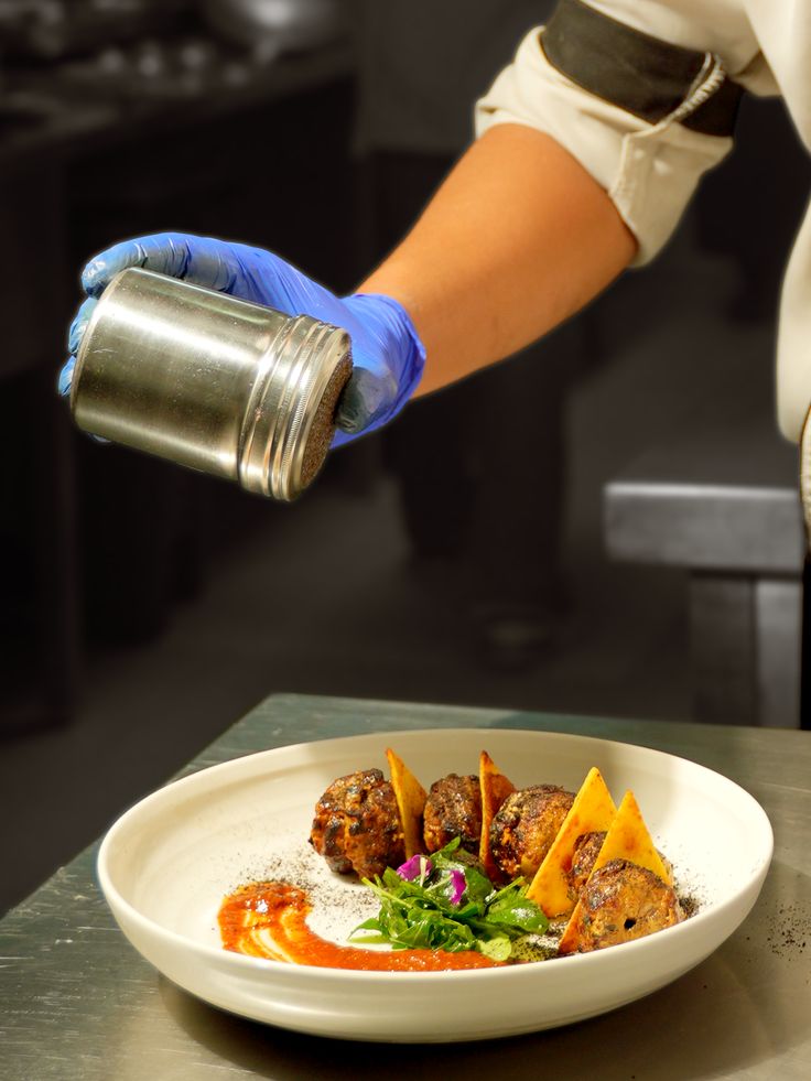Chef finishing a dish with fresh spices